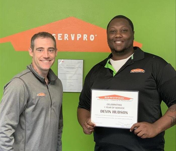 Two SERVPRO of St. Charles City employees standing side by side holding a certificate of 