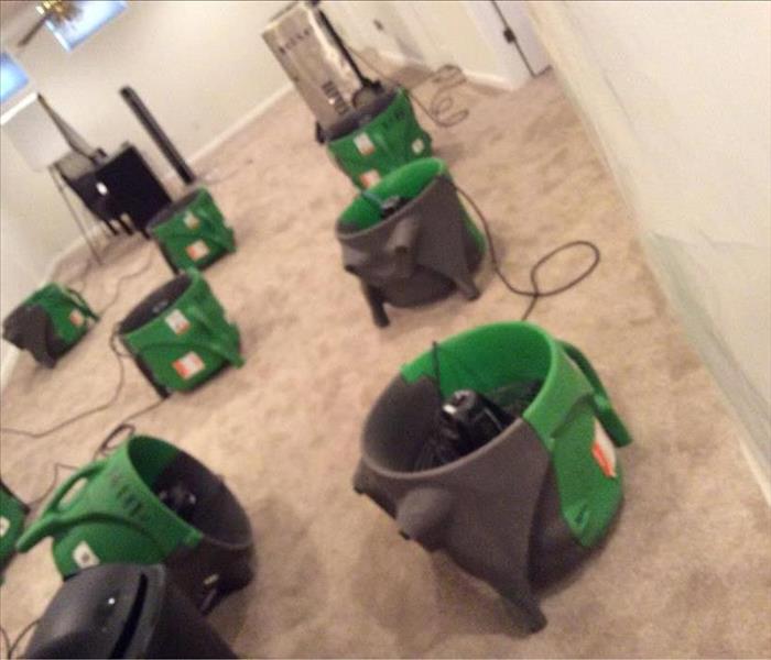 Water damaged carpet in O'Fallon home being dried by multiple green air movers.