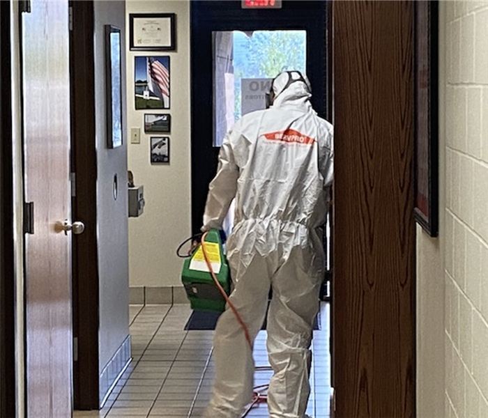 Man in personal protection equipment cleaning a fire department office