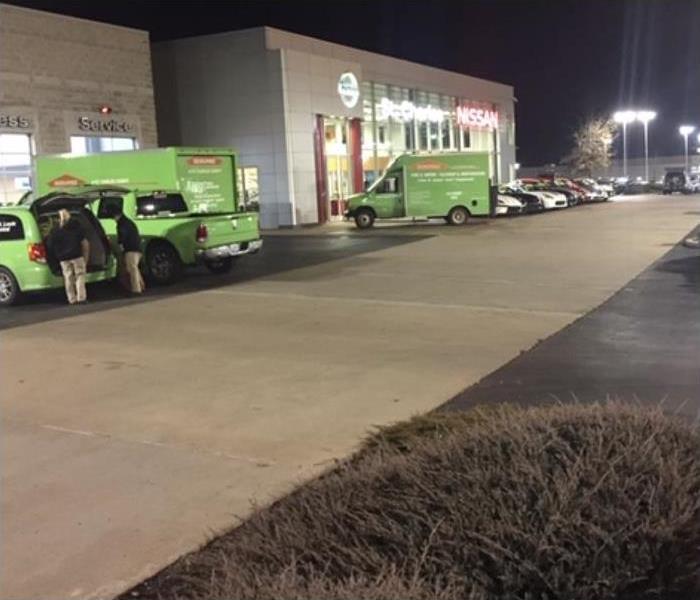 Green SERVPRO trucks in parking lot of a commercial building